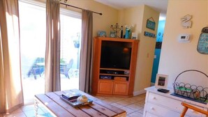 A room with a wooden table, a white dresser, a TV cabinet, and a window with curtains. - K7 Family Friendly, make some memories,clean, easy 2 bdrm 1.5 bath (St. Simons Island)