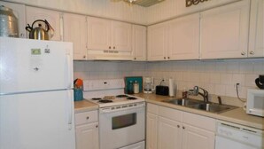 A compact kitchen with white cabinets, a stove, a sink, and a microwave. - K7 Family Friendly, make some memories,clean, easy 2 bdrm 1.5 bath (St. Simons Island)