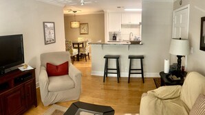 Un salon comprenant un téléviseur, un canapé, un fauteuil, une table basse et un ventilateur de plafond.