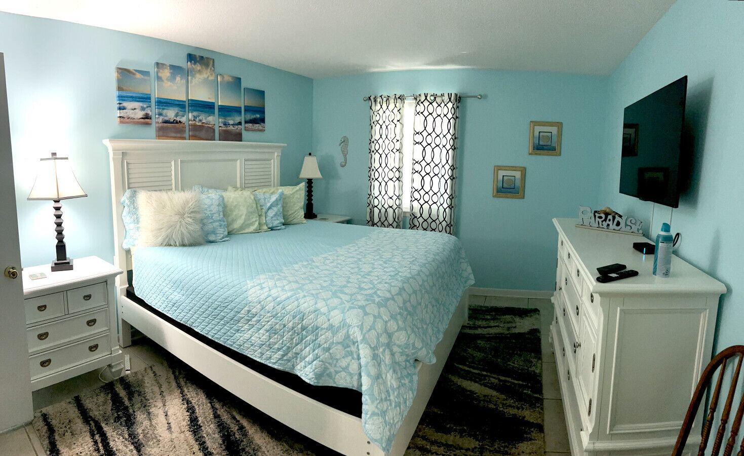 A bedroom with a bed, bedside tables, a dresser, and a television.