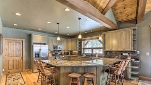 A spacious kitchen with a large island, wooden bar stools, and a refrigerator. - Beautiful Eureka Cabin Rental on Golf Resort! (Eureka)
