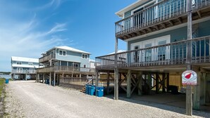 A beachfront property with multiple buildings, wooden decks, and a clear sky. - LAGOON VIEWS, OUTDOOR POOL, WALK TO DINING AND SHOPPING! (Gulf Shores)