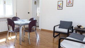 Una stanza con un tavolo da pranzo, quattro sedie, un letto singolo e un tavolino con una ciotola.