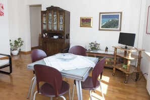 A dining area with a table, chairs, a cabinet, and a television.