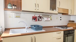 Una cucina con lavello, fornelli, forno e pensili.