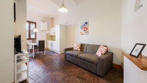 A living room with a sofa, a dining table, and a kitchen in the background. - Santa Maria Novella Classic by Mmega (Firenze)