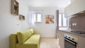 Una cocina moderna con horno empotrado y zona de comedor con sofá verde.