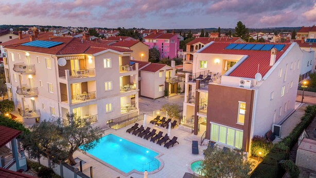 Un hotel con varios pisos, piscina y zonas de estar al aire libre.