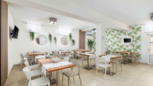 Un comedor con varias mesas y sillas, espejos redondos y televisores instalados en la pared.