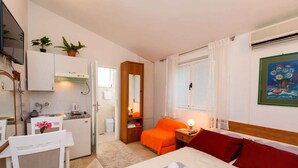 Ein kleines Hotelzimmer mit Bett, Schreibtisch, Küchenzeile und Bad.