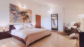 A modern bedroom with a large bed, a nightstand, a desk, and a chair.