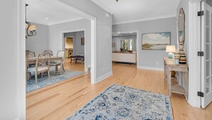 Ein geräumiges Wohnzimmer mit Holzboden, eine Essecke mit Holztisch und -stühlen sowie eine Küche im Hintergrund.