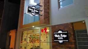 A hotel with a prominent neon sign, a brick facade, and large windows. - Villalba Boutique Hotel (Valledupar)