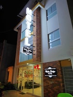 Un hotel con llamativo letrero de neón, fachada de ladrillo y grandes ventanales.