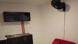 A compact living space with a kitchenette, a dining table, a red sofa, and a ceiling-mounted projector. - Villalba Boutique Hotel (Valledupar)