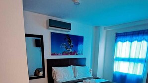 A bedroom with a bed, a wall-mounted air conditioner, a painting, and a window with blue curtains. - Villalba Boutique Hotel (Valledupar)
