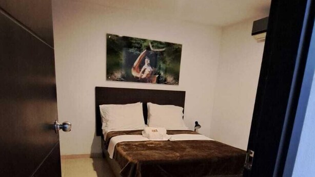 A bedroom with a bed, a headboard, a painting on the wall, and a door. - Villalba Boutique Hotel (Valledupar)