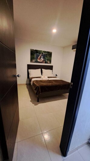 A bedroom with a bed, a headboard, a painting on the wall, and a door. - Villalba Boutique Hotel (Valledupar)