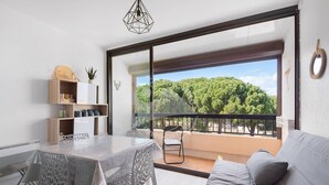 A modern living room with a balcony, a dining area with a table and chairs, and a sofa.