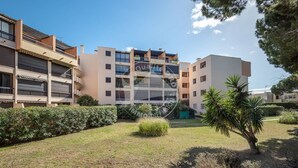 A multi-story residential building with balconies, a well-maintained lawn, and surrounding greenery.
