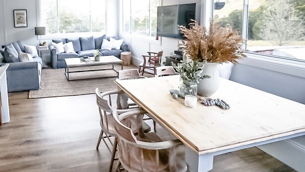 Una sala de estar moderna con un ventanal grande, un juego de sofá, una mesa de comedor y un televisor.