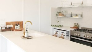 Una cocina moderna con armarios blancos, una isla central, luces colgantes y una estufa de acero inoxidable.