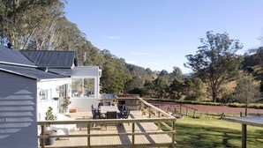 Una casa moderna con terraza, comedor y vistas a un paisaje montañoso.