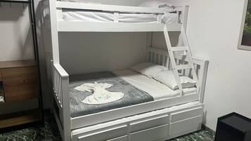 Uma cama de beliche com escada, uma mesinha de cabeceira e uma gaveta.