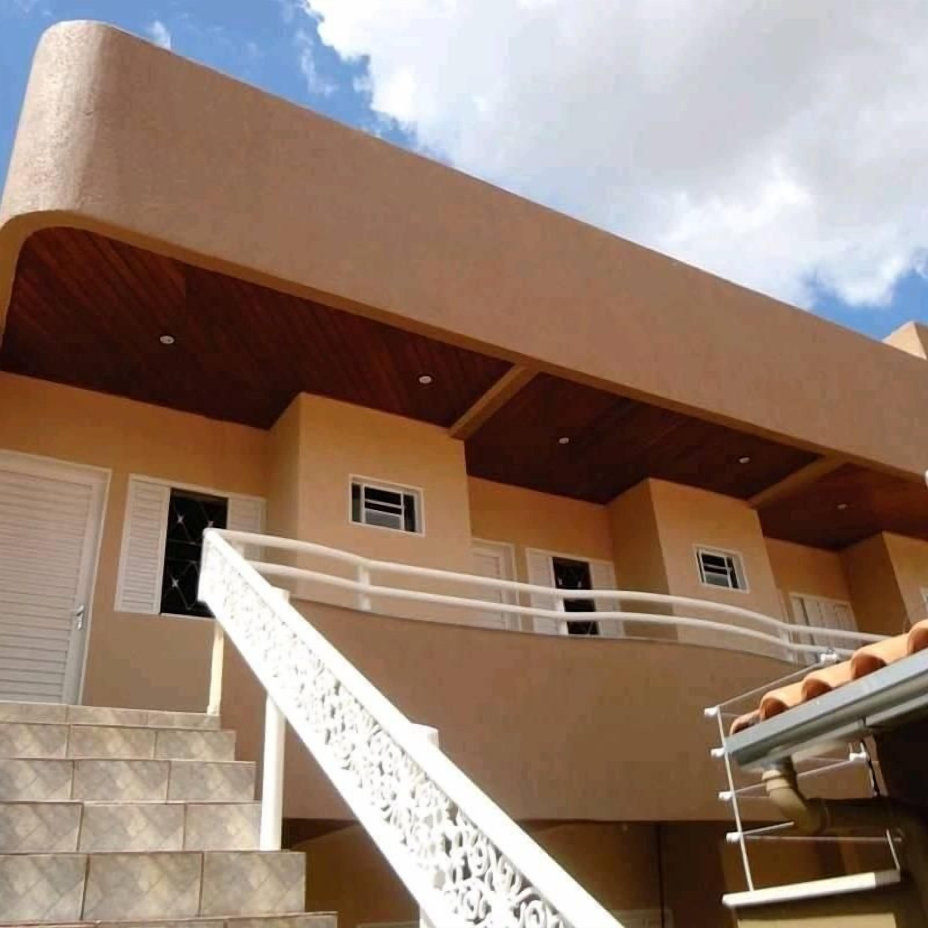 A building with a beige exterior, a staircase with white railings, and multiple windows.