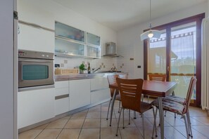 Una cocina moderna con horno empotrado, un comedor con mesa y sillas, y un ventanal que proporciona luz natural.