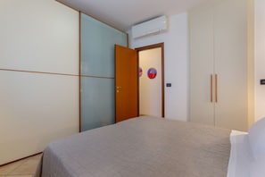 A bedroom with a bed, a wardrobe, and a door with a circular decoration. - Apartment located on the ground floor of a modern terraced house with private entrance.Beautiful private garden with table and chairs for outdoor dining or simply relaxing.In 75 square meters of space it accommodates 6 people with a double bedroom, a sin (Ferrara)