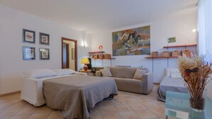 Un dormitorio con cama, sofá, escritorio y un cuadro en la pared.