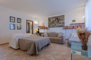 Une chambre à coucher avec un lit, un canapé, un bureau et un tableau accroché au mur.