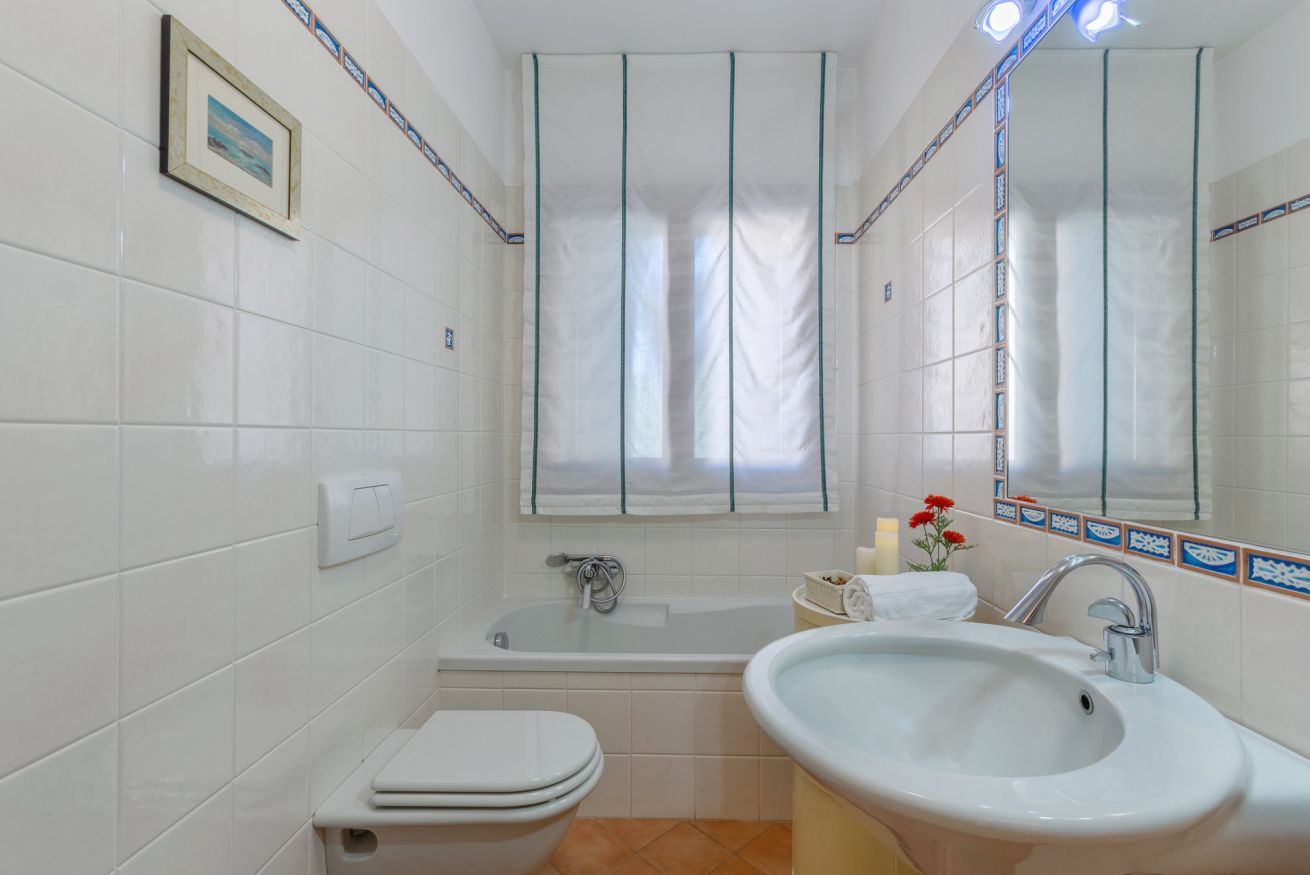 Un baño con inodoro, bañera, lavabo y espejo.
