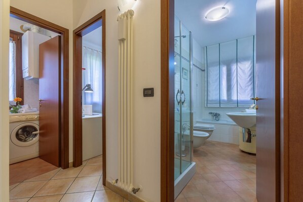 A bathroom with a glass shower enclosure, a toilet, and a sink.