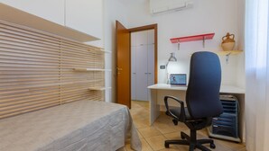 Un dormitorio con cama, un escritorio con ordenador, una silla y un armario.