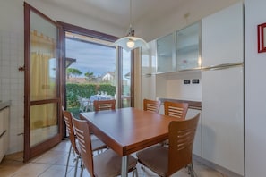Ein Essbereich mit Tisch und Stühlen, einem Kühlschrank und einer Glastür, die auf eine Terrasse führt.