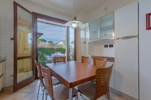 Un comedor con una mesa y sillas, un refrigerador y un puerta corrediza de vidrio que da a un patio.