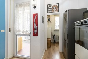 A kitchen with a refrigerator, oven, and a window with a curtain. - GuestHost - Cozy and spacious apartment that accommodates 4 people with great comfort, located in Vanchiglia district, at the gates of historic center, easily reachable by public transport or a 15-minute walk. The flat boasts a double exposure with a bal (Torino)