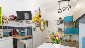 Cozinha moderna com área de jantar, televisão fixada acima do balcão e diversos eletrodomésticos.