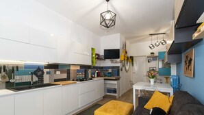 Uma cozinha moderna com armários brancos, uma ilha central e um espaço de jantar com mesa e cadeiras.
