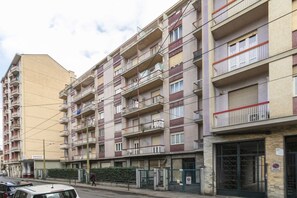 A multi-story residential building with balconies, a parking area, and a pedestrian walkway. - GuestHost - Cozy and spacious apartment that accommodates 4 people with great comfort, located in Vanchiglia district, at the gates of historic center, easily reachable by public transport or a 15-minute walk. The flat boasts a double exposure with a bal (Torino)