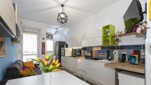 Uma cozinha moderna com armários brancos, bancada de madeira e um espaço de refeições com mesa branca e tulipas coloridas.