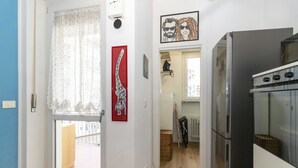 Uma cozinha com geladeira, forno e janela com cortina.