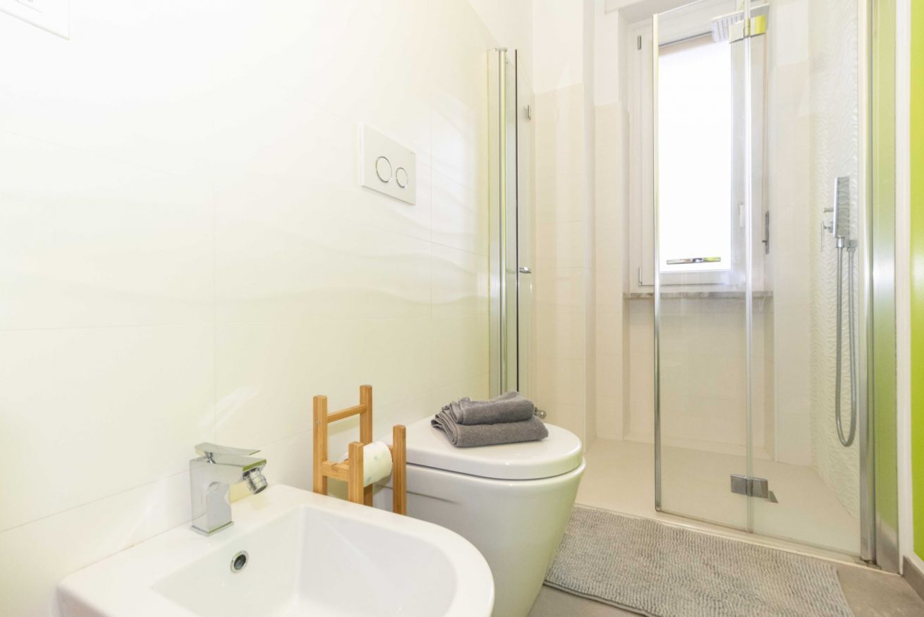 Un baño moderno con bañera, inodoro y ducha con mampara de vidrio.