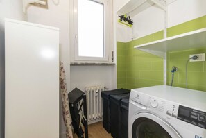 A laundry room with a washing machine, a radiator, and a window. - GuestHost - Cozy and spacious apartment that accommodates 4 people with great comfort, located in Vanchiglia district, at the gates of historic center, easily reachable by public transport or a 15-minute walk. The flat boasts a double exposure with a bal (Torino)