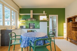 A compact kitchen with a dining area, green walls, and a view through the window.