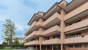 Un edificio de varios pisos con balcones, un patio empedrado y cielo despejado.
