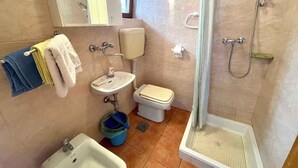 A bathroom with a shower, toilet, sink, and a mirror.