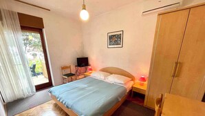 A bedroom with a bed, a desk with a computer, a TV, and a wardrobe.